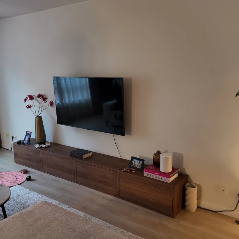 Woonkamerwand achter een laag tv-meubel, egaal afgewerkt zonder rolranden of vlekken