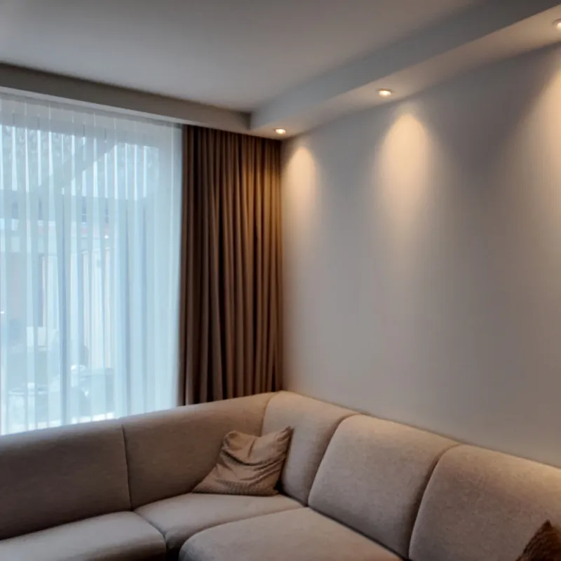 Zithoek met een egaal afgewerkte wand en plafond, spots die het vlak van opzij aanlichten